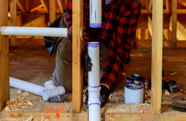 Plumber installing primer and glue PVC pipe at construction new home