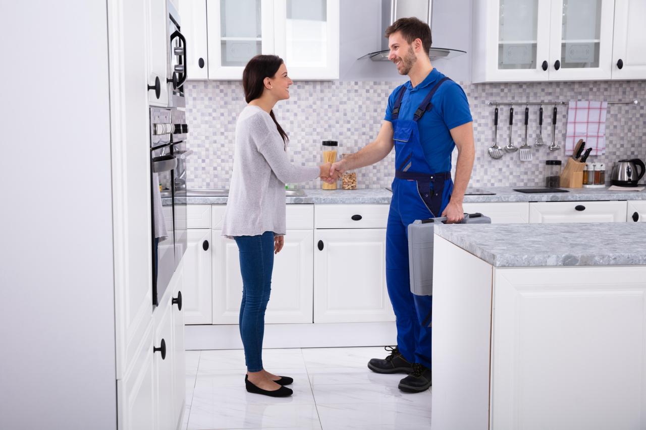 Technician and homeowner shaking hands in a modern kitchen after completing a service.