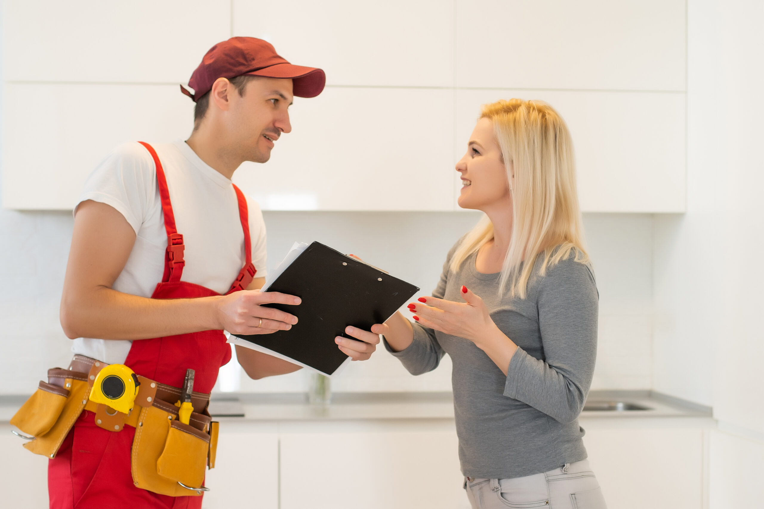Technician in red uniform discussing repair details with a smiling homeowner.