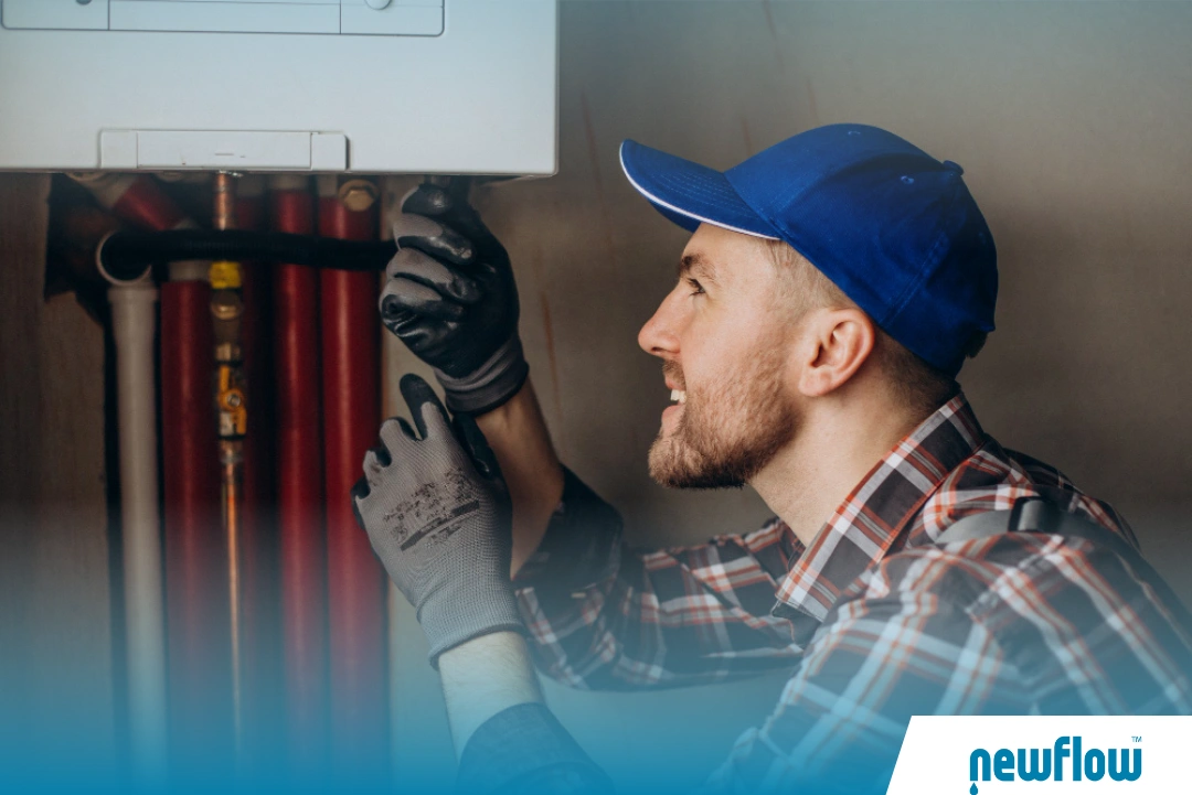Technician installing a residential water heater with tools and protective gloves.